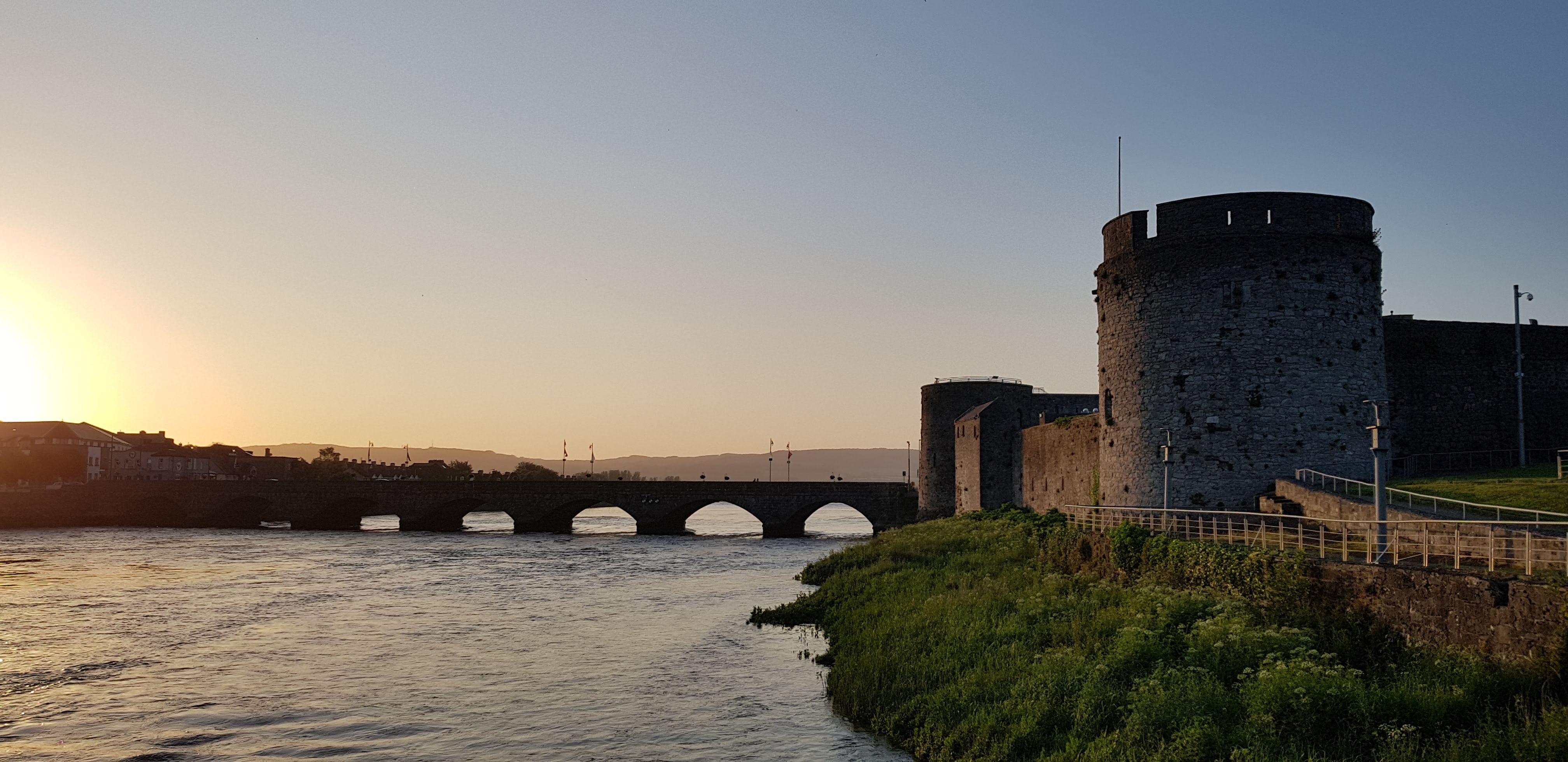 Picture of a castle next to a river at sunset