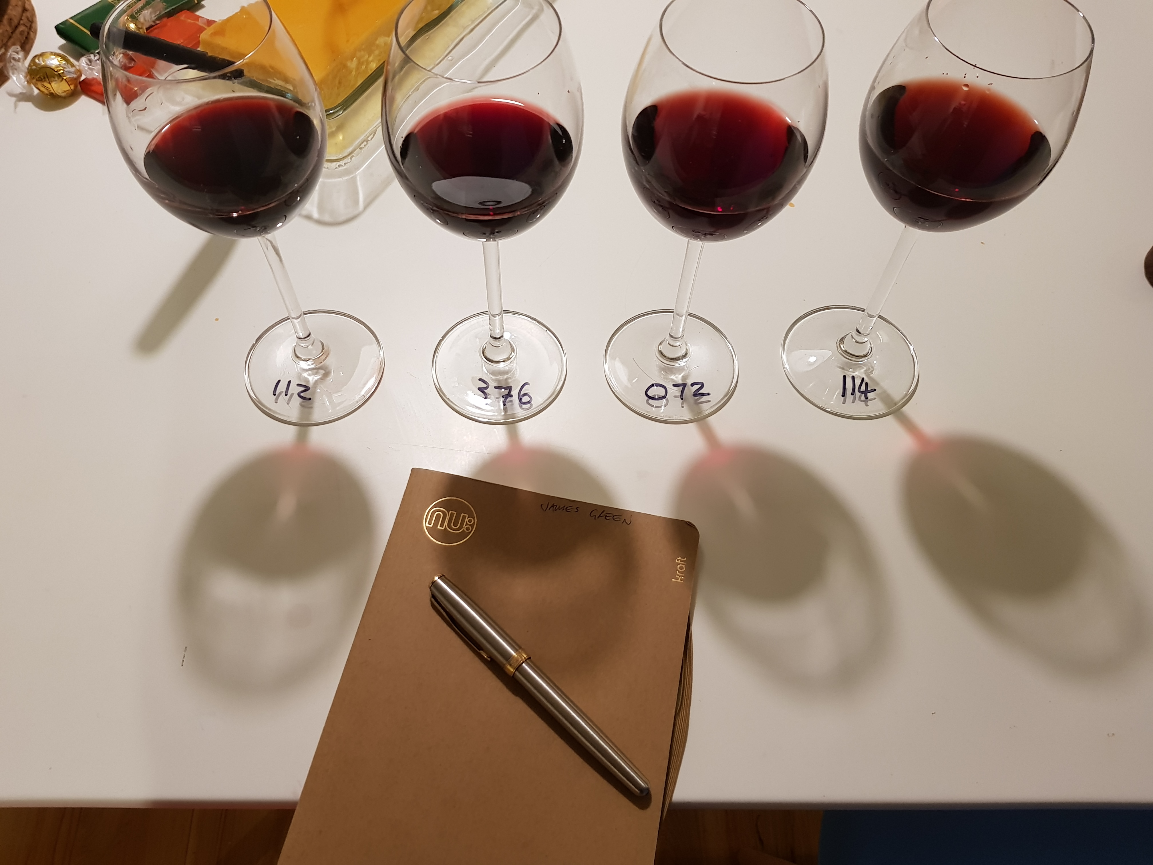 4 numbered glasses of red wine, with a notebook and pen, reading for tasting
